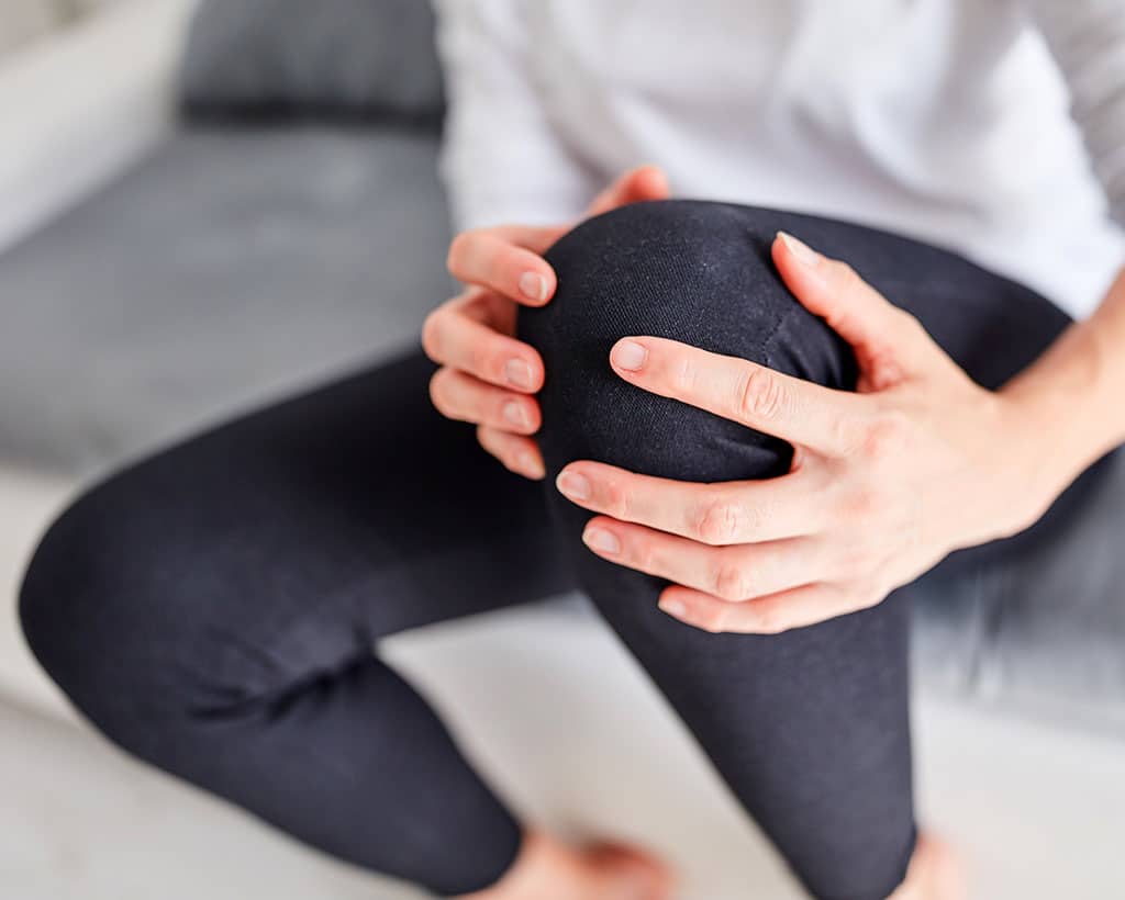 Patientin hält schmerzendes Knie in Lübecker Physiotherapiepraxis